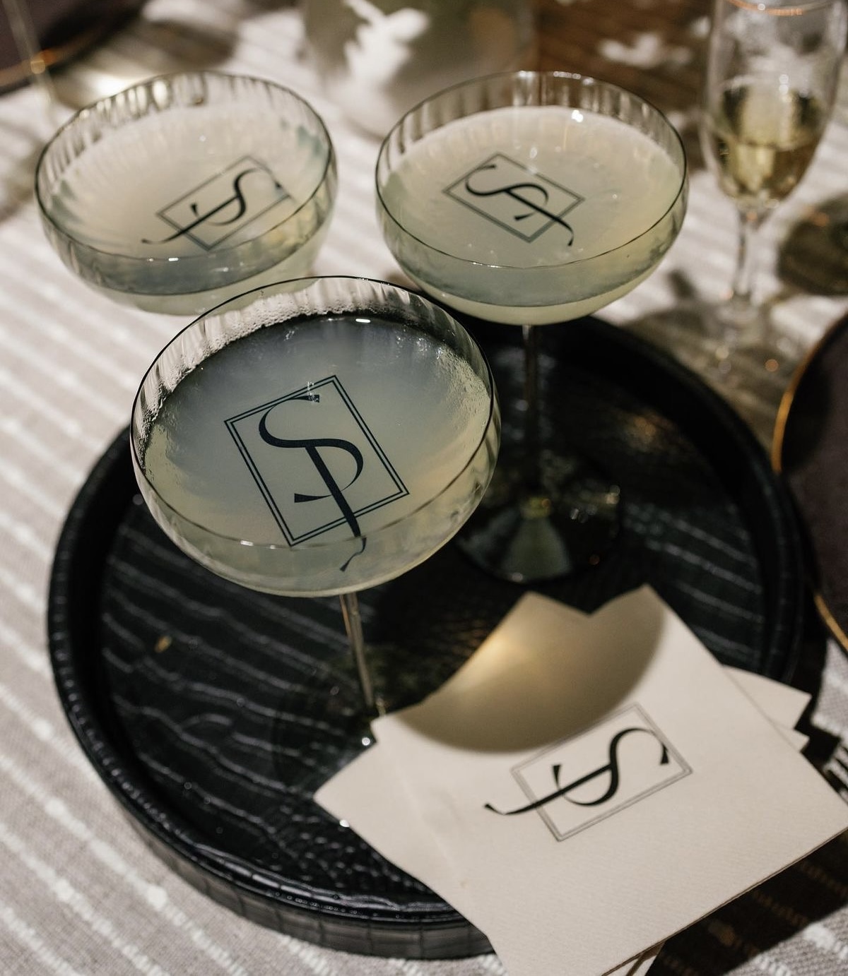 Signature cocktails in monogrammed coupes on a tray with custom napkins